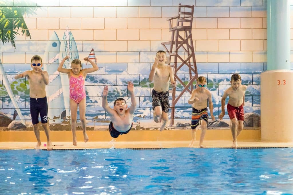 Kids jump into a pool.