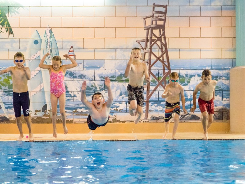 Kids jump into a pool.
