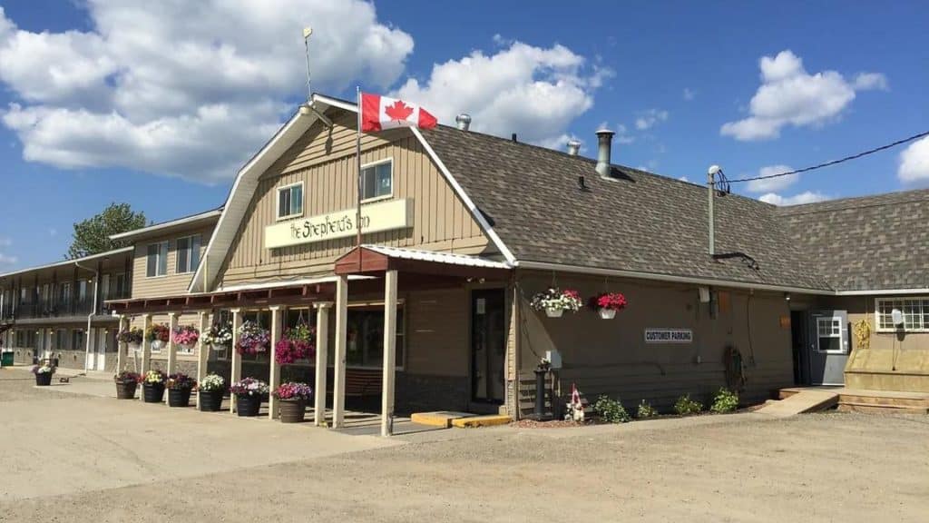 The front entrance to The Shepard's Inn, with a Canada Flag on the porch roof and flowers hanging.