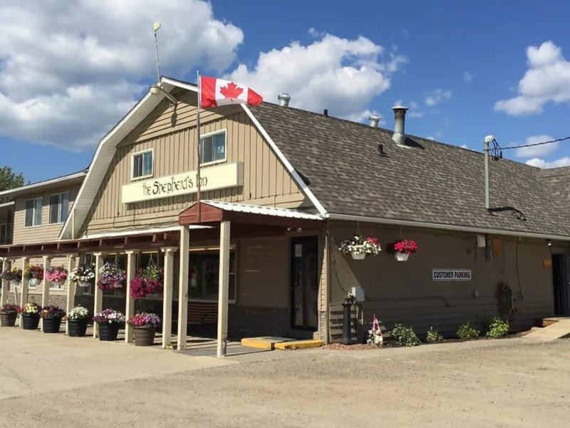 The front entrance to The Shepard's Inn, with a Canada Flag on the porch roof and flowers hanging.