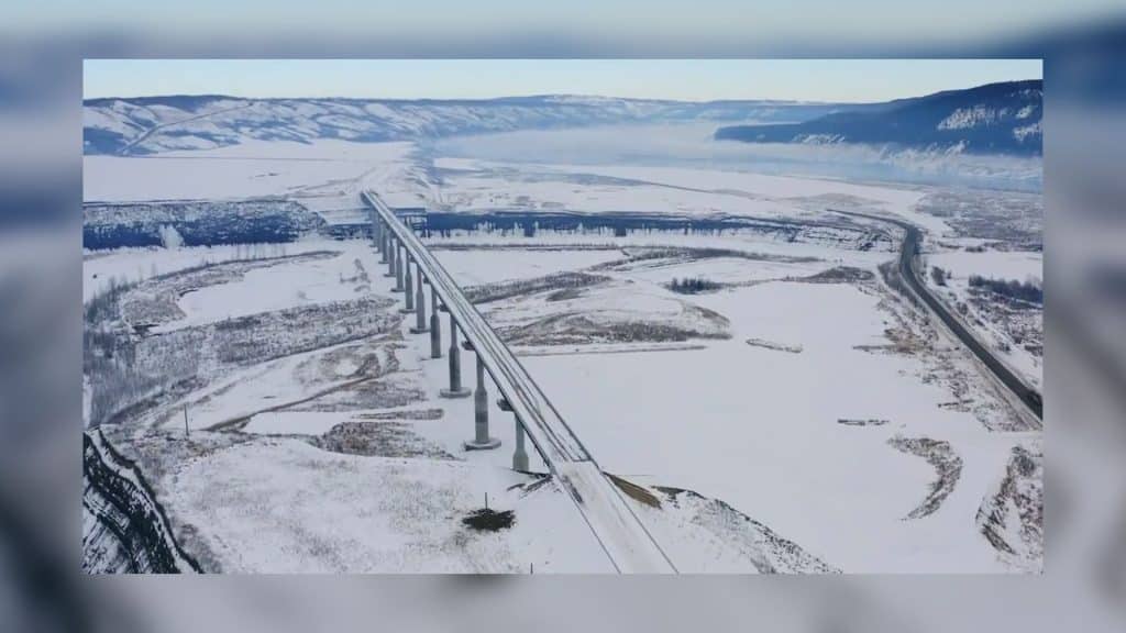 A snowy highway with a large bridge.