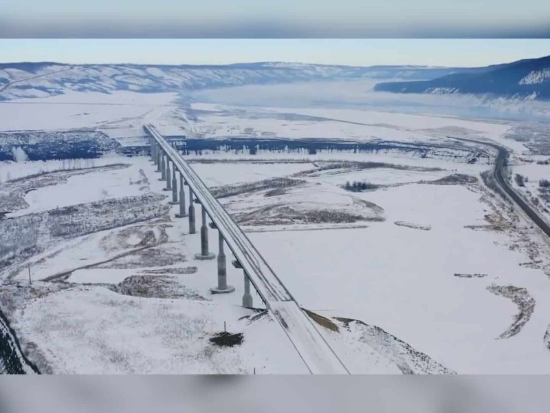 A snowy highway with a large bridge.