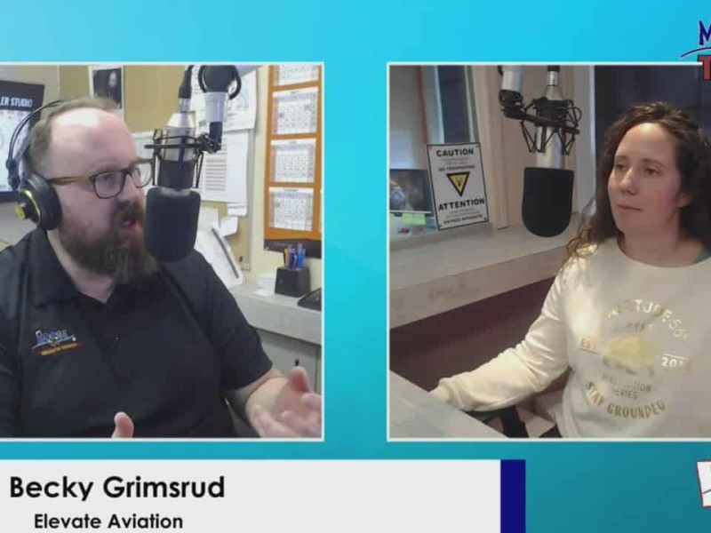 Person on left in black shirt behind microphone, person on right in white shirt behind microphone