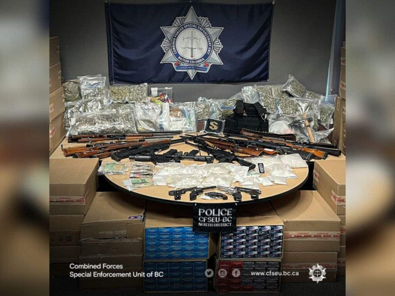 A table full of seized items, including drugs, guns, and drug paraphernalia.