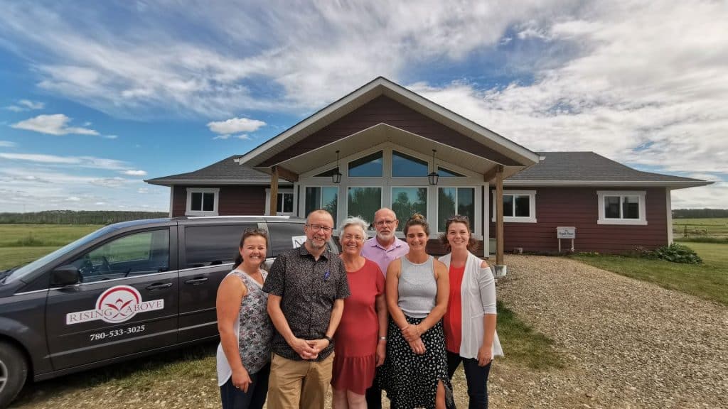 A group of people stand in front of a large, red, house-like building.