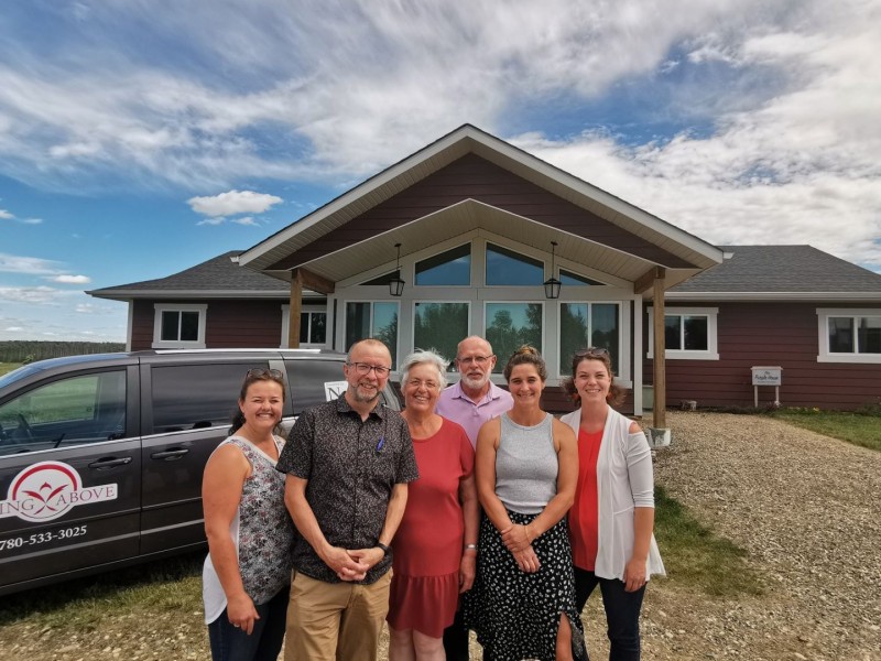 A group of people stand in front of a large, red, house-like building.
