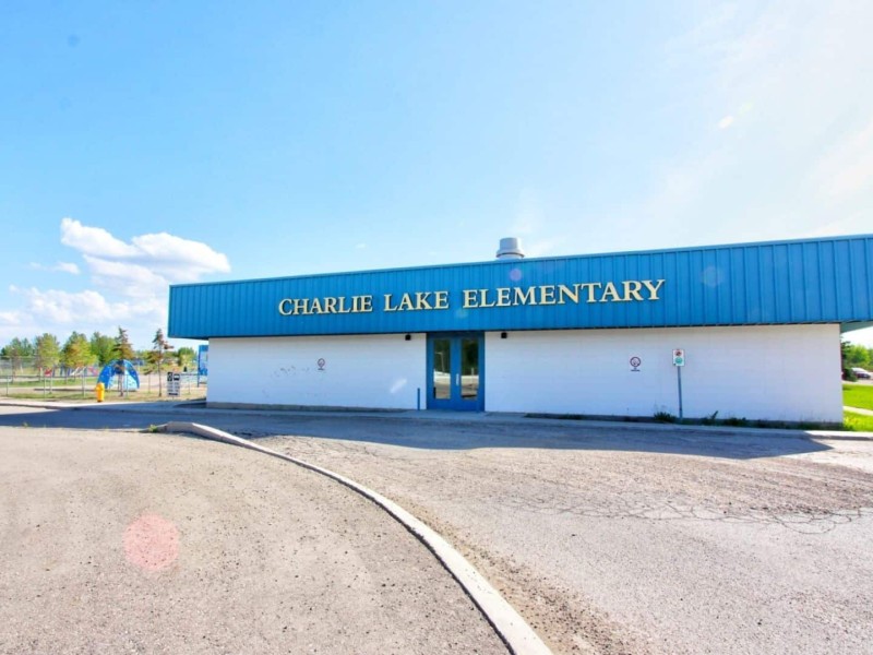 A picture of the Charlie Lake Elementary school, a blue and white building with a playground in the background.