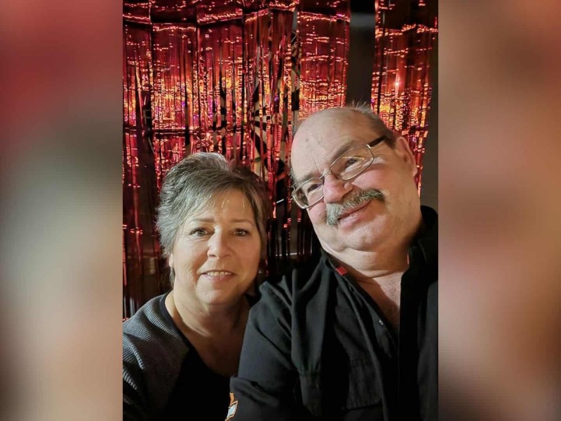 A man and his wife in front of red streamers.