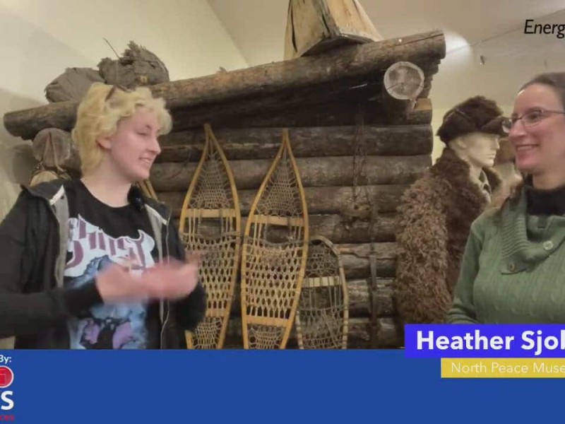 Two people standing in front of an old log cabin