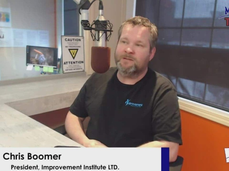 Person with black t-shirt sitting behind a desk and microphone