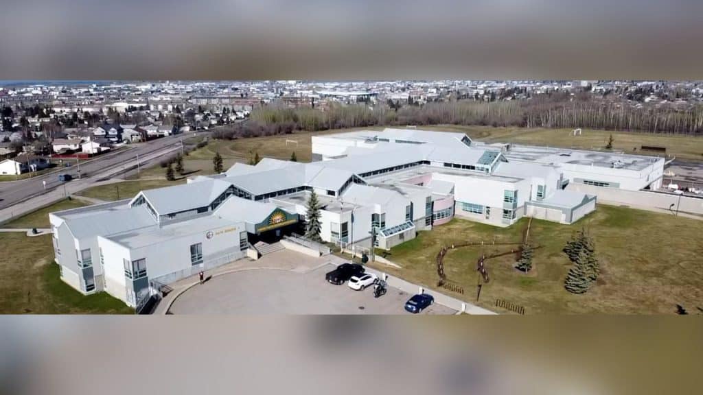 An aerial view of North Peace Secondary School with cars in the front parking lot and overlooking the City of Fort St. John.