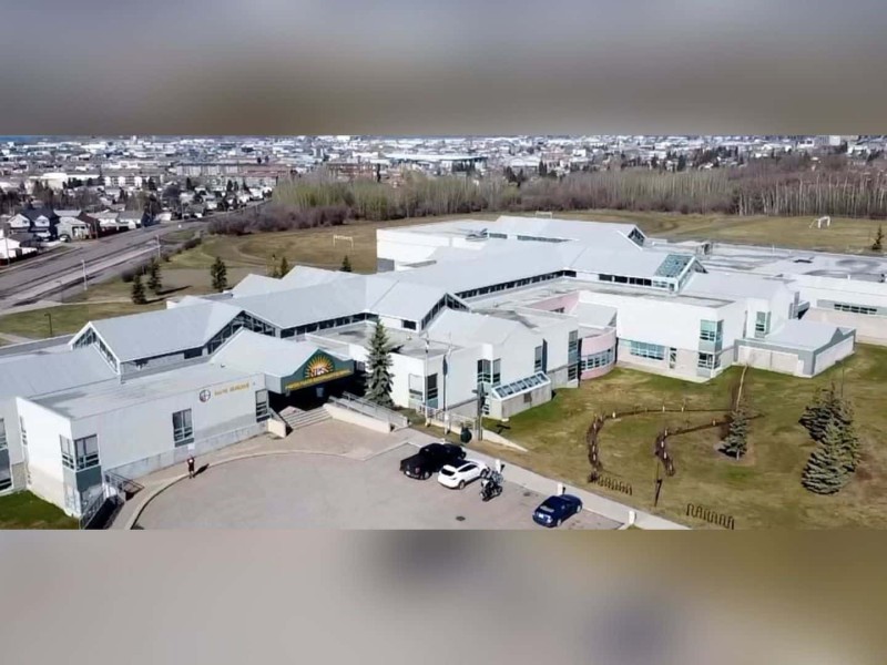 An aerial view of North Peace Secondary School with cars in the front parking lot and overlooking the City of Fort St. John.