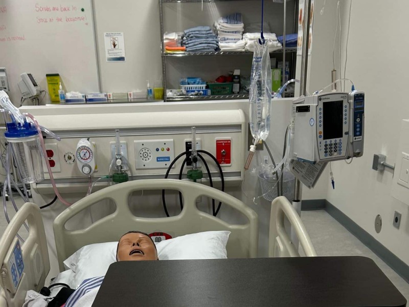A lab set up for students in the Northern Baccalaureate Nursing program with a dummy in a bed and a whiteboard in the background.