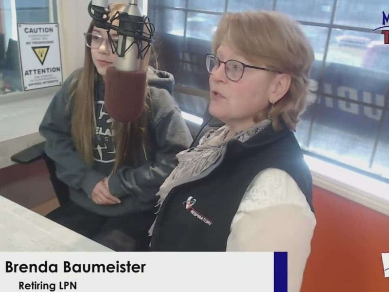 Two people sitting in front of a microphone