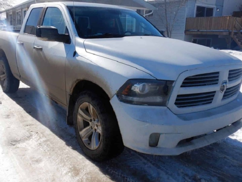 A white Dodge Ram sitting in a snowy driveway in front of a mobile home.