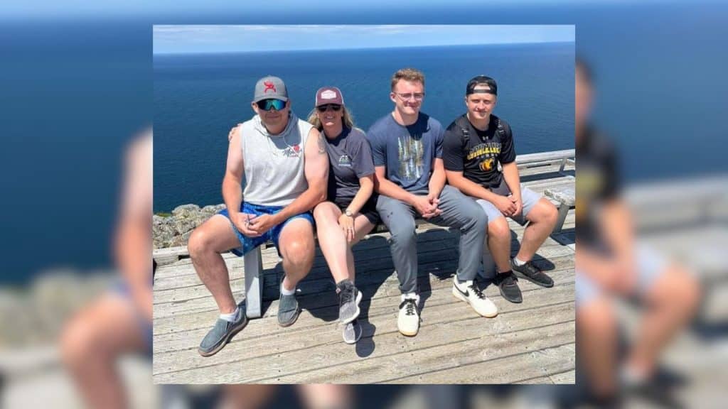 A man and his family sitting besides the water.