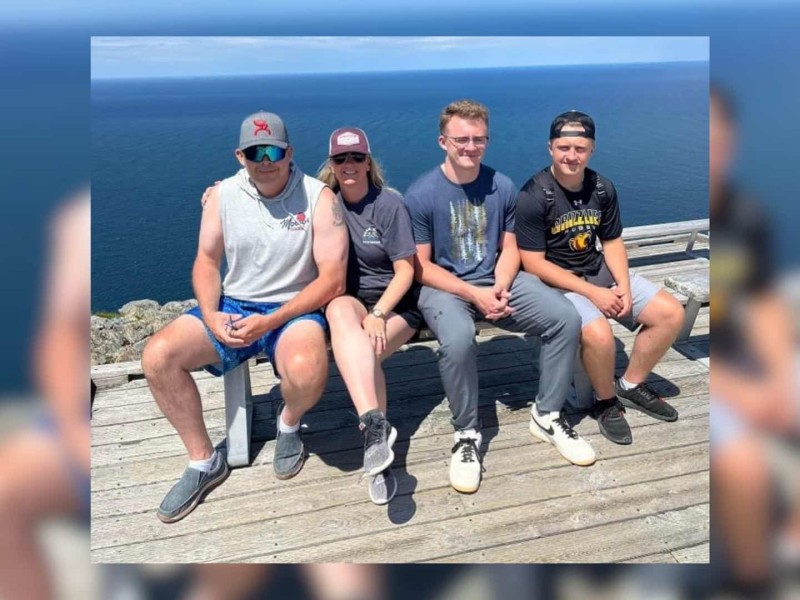 A man and his family sitting besides the water.
