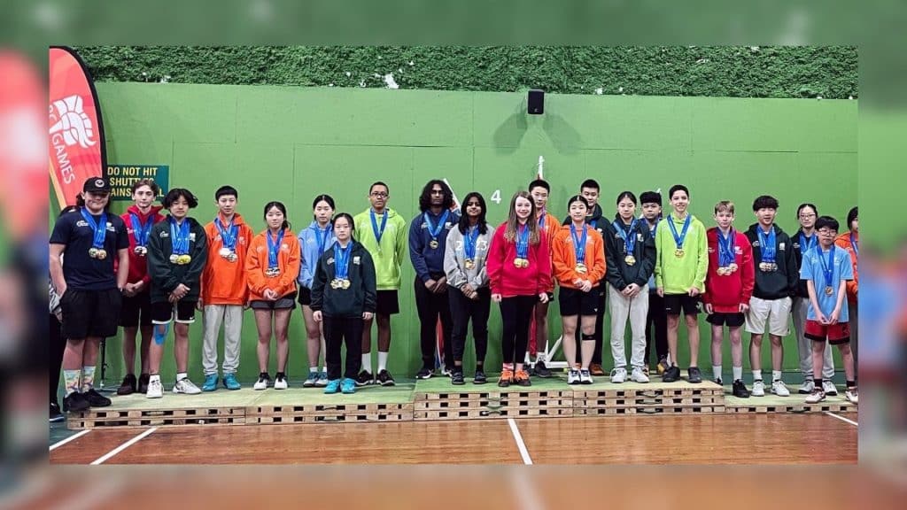 A large group of kids standing on platforms with medals around their necks in what appears to be a school gym.