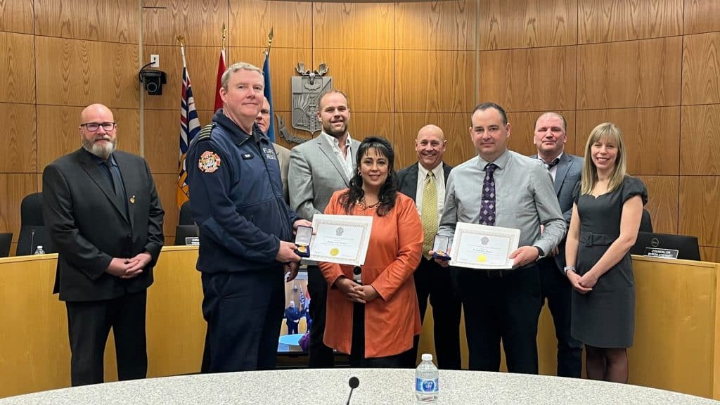 A group of people stand in a wood paneled room.