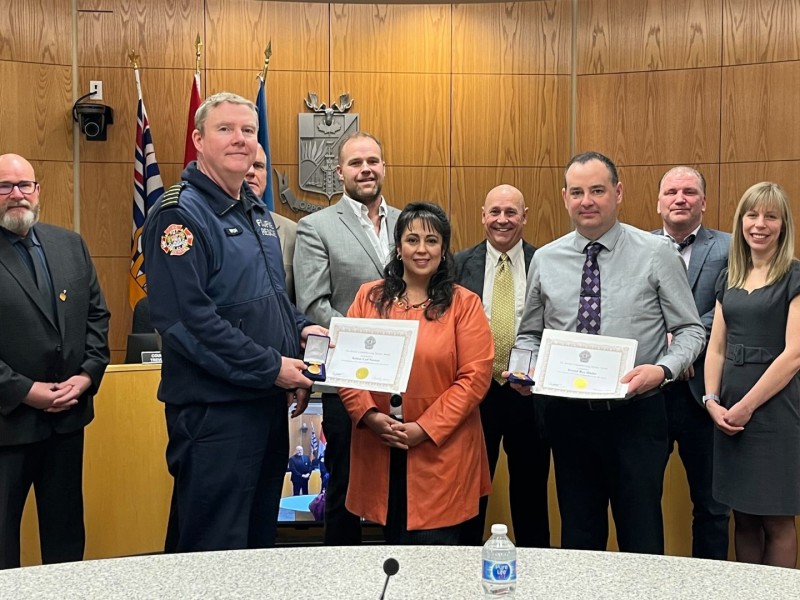 A group of people stand in a wood paneled room.