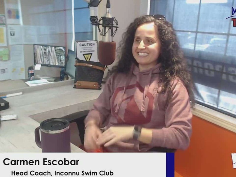 Person in red hoodie smiling behind a microphone
