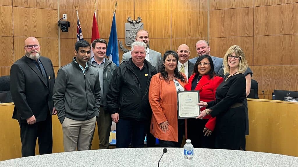 A group of people pose for a photo in a wood paneled room.
