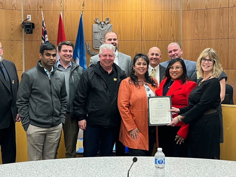 A group of people pose for a photo in a wood paneled room.