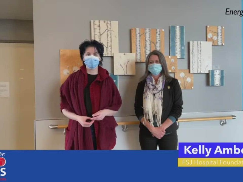 Two people standing in front of wall wearing masks