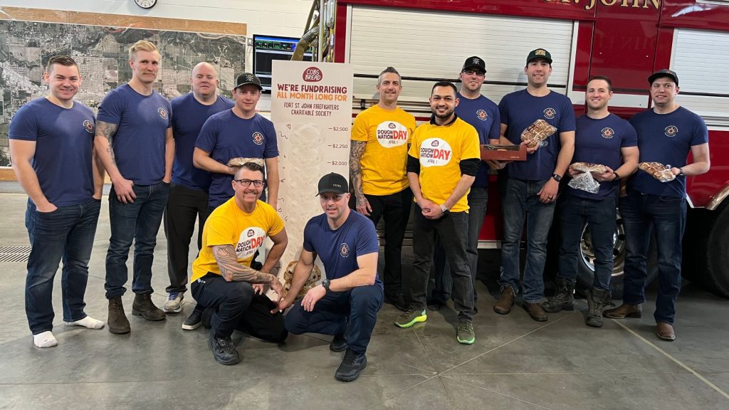 A group of firefighters and Cobs Bread staff in front of a fire engine.