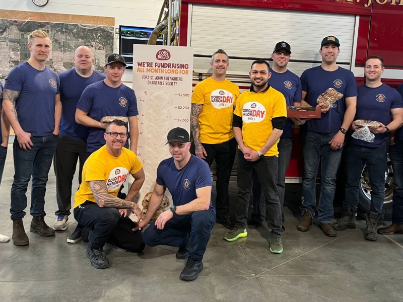 A group of firefighters and Cobs Bread staff in front of a fire engine.