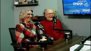Two people sitting at a table with microphones