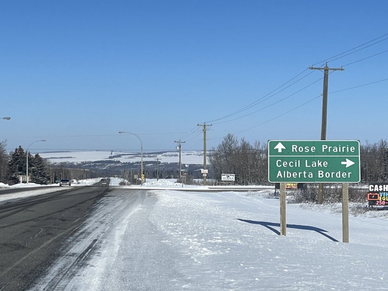 A road in the winter. Snow along the sides, and a green road sign on the right.