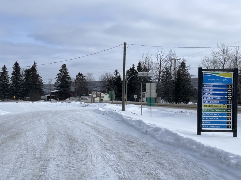 A road with a sign on the right hand side for directions around a town called Hudson's Hope.