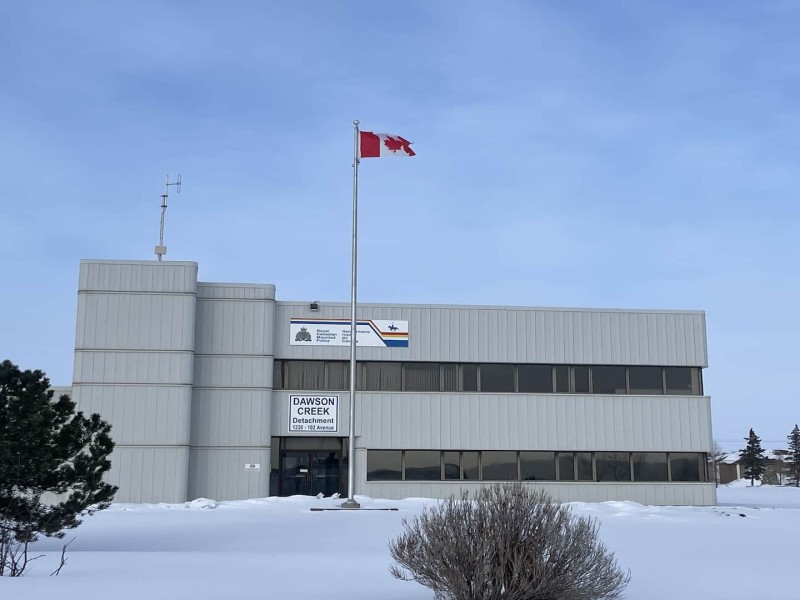 A large grey building with the Canadian flag outside of it.