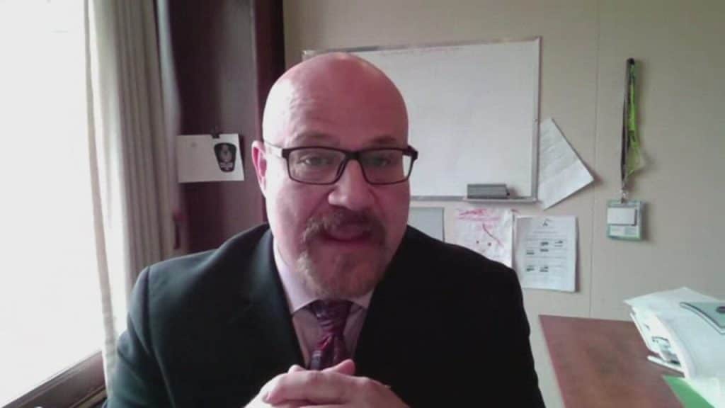 Person sitting in front of white board with hands clasped