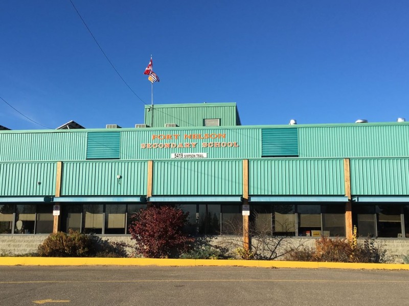 A blue building and parking lot. "Fort Nelson Secondary School" with the BC and Canadian flags.
