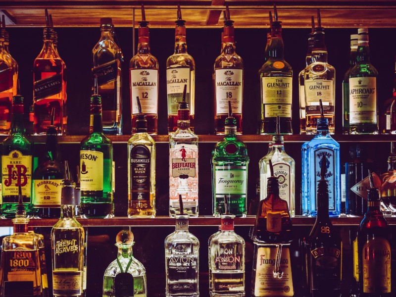 Three shelves full of assorted types of liquor.