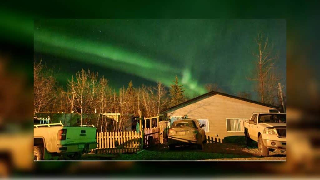 A trailer home at night with the northern lights in the sky.