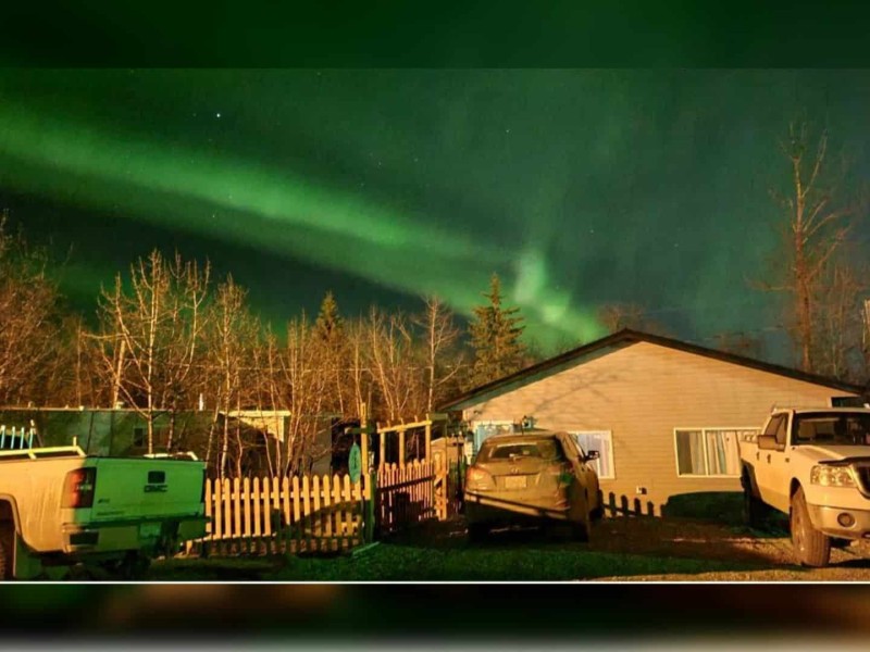 A trailer home at night with the northern lights in the sky.