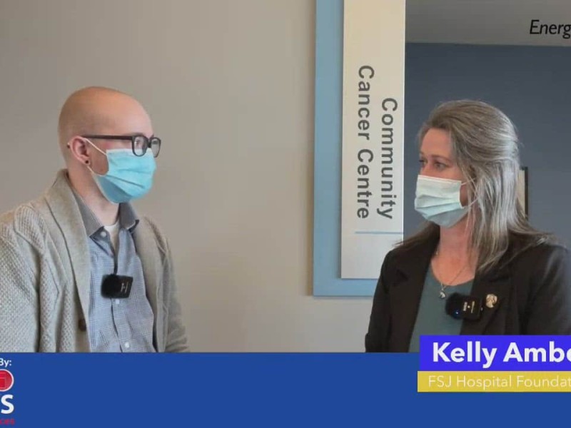 Person on left with beige sweater wearing a mask, person on right in black blazer wearing a mask