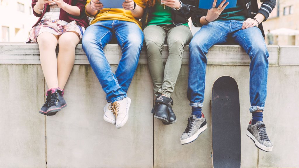 A group of teenagers sit together on a concrete wall.
