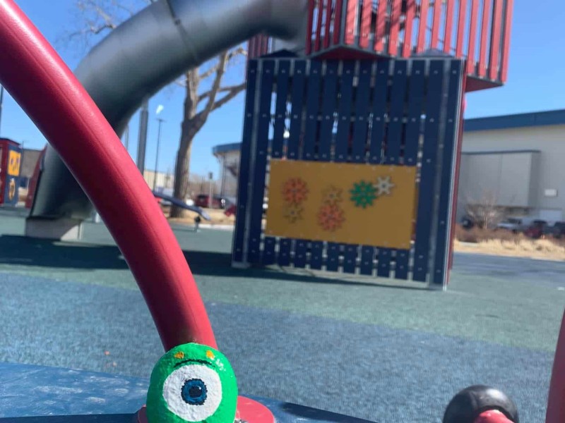 A rock painted like Mike from Monster's Inc sitting in a playground.
