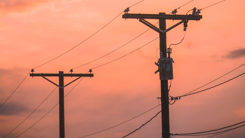 Power lines in front of an orange sunset.