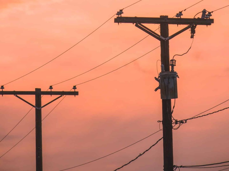 Power lines in front of an orange sunset.