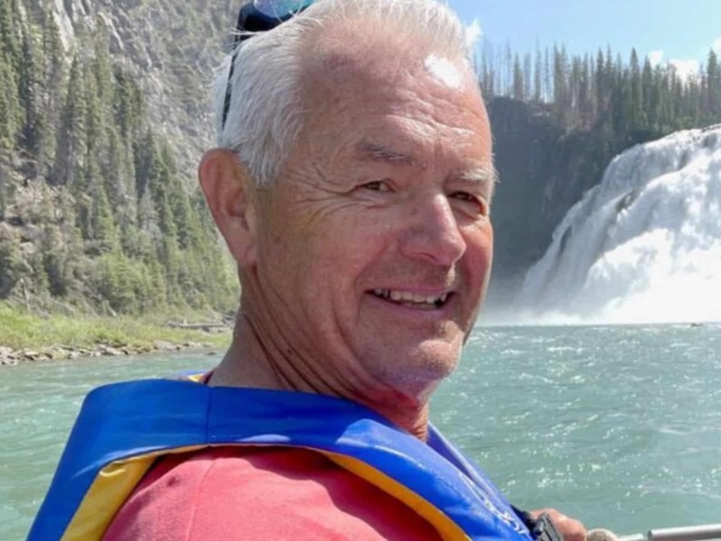An older white man with white hair wearing a red shirt and a lifejacket.