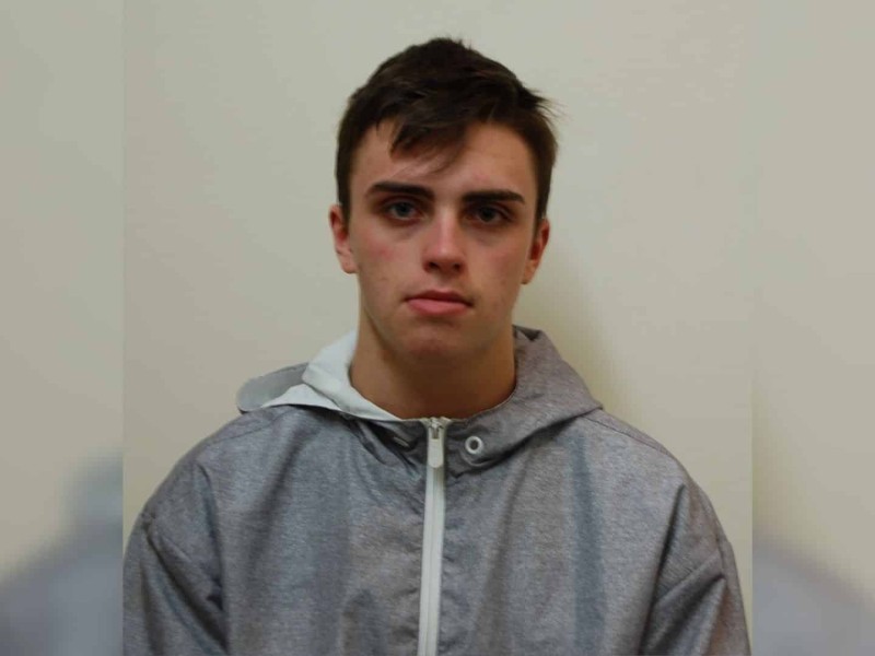 A picture of a young man in a grey jacket in front of a light background.