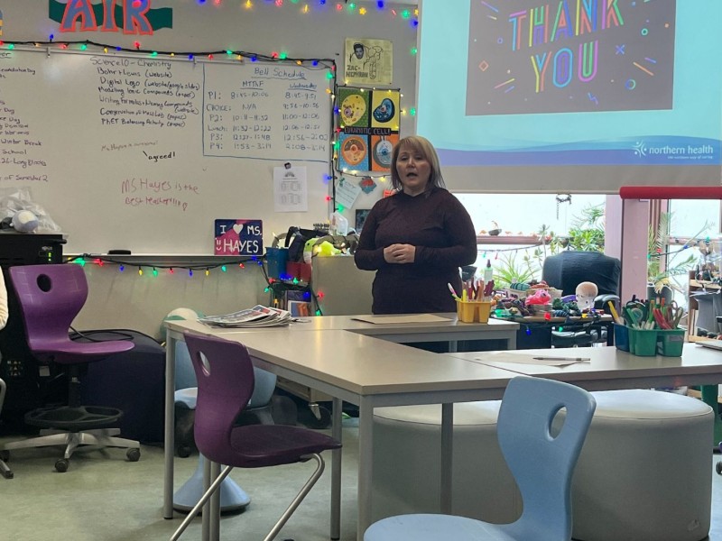 Two women present to a colourful, high school class room.