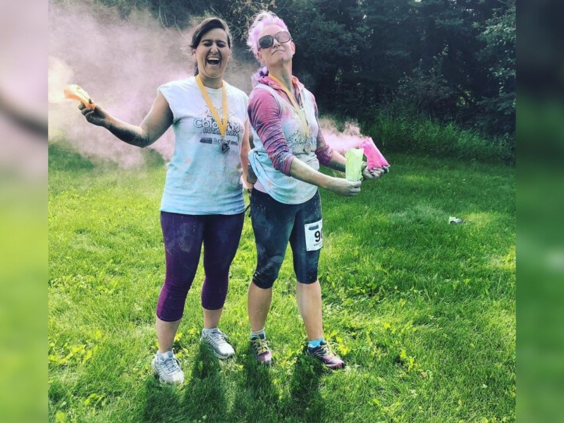 Two women in running attire covered in green and pink pigment.