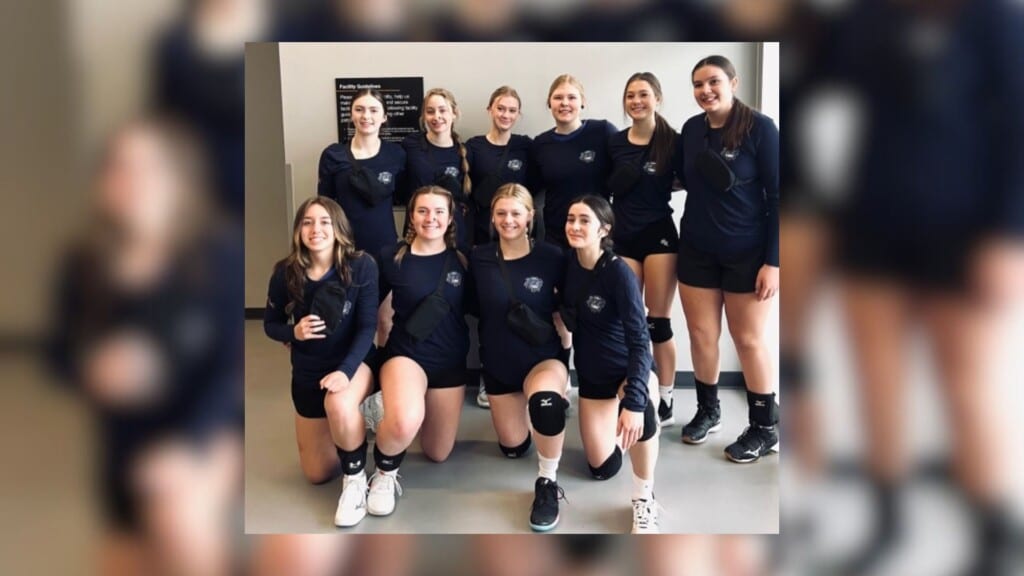 A group of volleyball players dressed in navy blue and white uniforms.