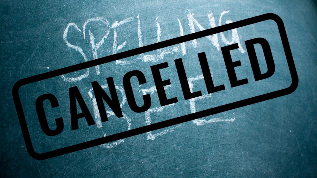 "Spelling Bee" written in white on a green chalkboard, with black writing saying "Cancelled" over top of it.